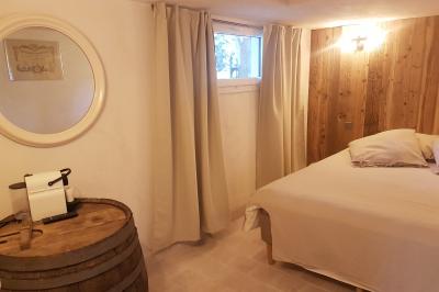 Table en pierre sous une voûte en pierre, avec un pot de fleurs et des outils anciens accrochés au mur.