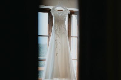 Table en pierre sous une voûte en pierre, avec un pot de fleurs et des outils anciens accrochés au mur.