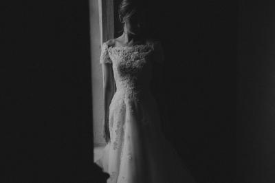 Table en pierre sous une voûte en pierre, avec un pot de fleurs et des outils anciens accrochés au mur.