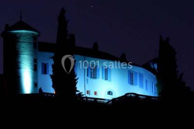 Table en pierre sous une voûte en pierre, avec un pot de fleurs et des outils anciens accrochés au mur.