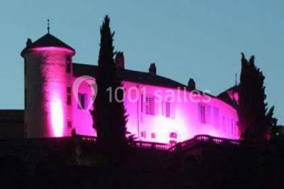 Table en pierre sous une voûte en pierre, avec un pot de fleurs et des outils anciens accrochés au mur.