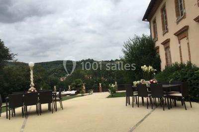 Couloir avec parquet en bois, murs verts décorés, table avec cadres et bougies, et rideaux verts aux fenêtres.