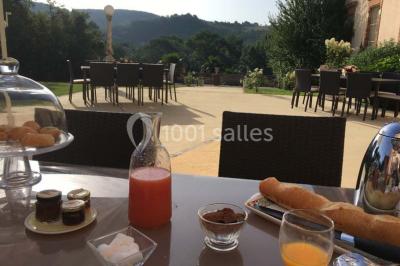 Couloir avec parquet en bois, murs verts décorés, table avec cadres et bougies, et rideaux verts aux fenêtres.