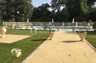 Couloir avec parquet en bois, murs verts décorés, table avec cadres et bougies, et rideaux verts aux fenêtres.
