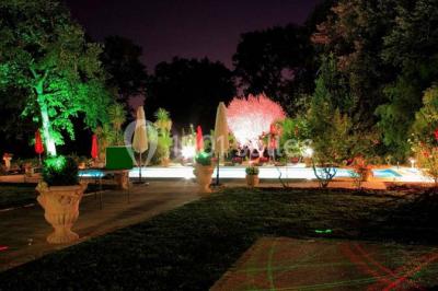 Couloir avec parquet en bois, murs verts décorés, table avec cadres et bougies, et rideaux verts aux fenêtres.