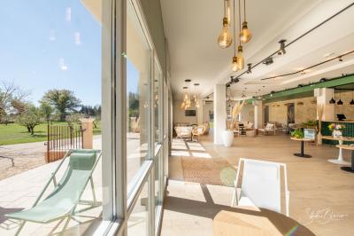 Salle lumineuse avec mobilier en bois et rotin, canapés blancs, décorations naturelles et grandes fenêtres donnant sur l…