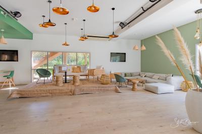 Salle lumineuse avec mobilier en bois et rotin, canapés blancs, décorations naturelles et grandes fenêtres donnant sur l…