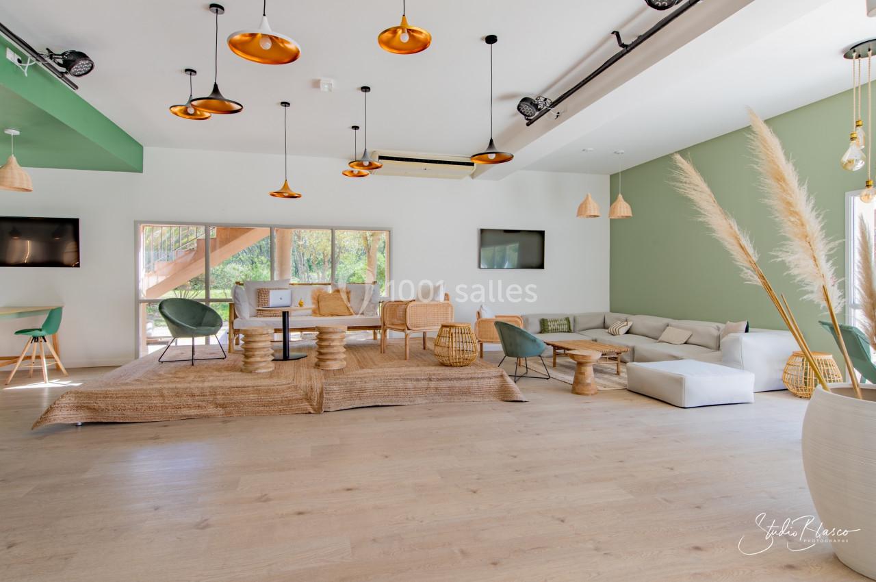 Salle lumineuse avec mobilier en bois et rotin, canapés blancs, décorations naturelles et grandes fenêtres donnant sur l…