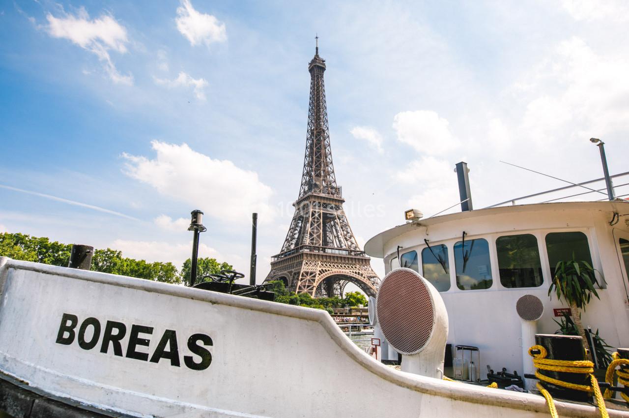 Vue de la tour Eiffel depuis les quais de la Seine, avec un bateau nommé ’Boreas’ au premier plan.