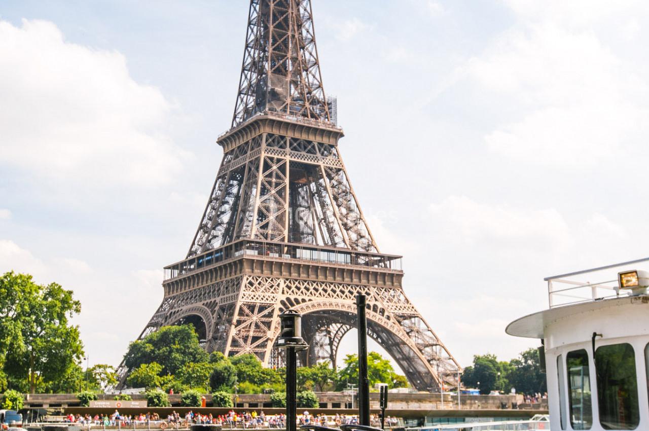 Vue de la tour Eiffel depuis la Seine avec une péniche blanche portant le nom ’Boreas’ au premier plan.