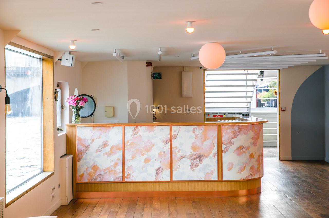 Comptoir décoré de motifs marbrés dans un espace lumineux avec parquet, grandes fenêtres et vue sur l'extérieur.