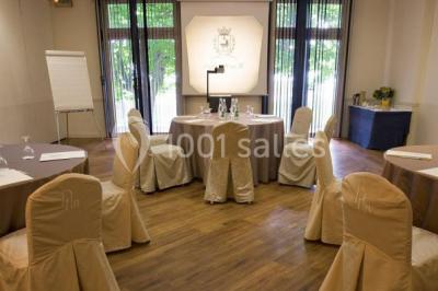 Deux tables de massage recouvertes de draps beiges, avec une vue sur un paysage urbain et verdoyant à travers une fenêtre.