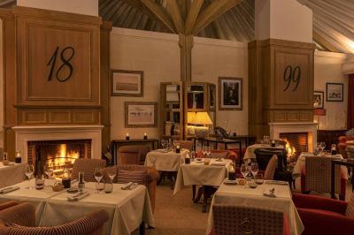 Panier de fruits frais sur une table en verre avec deux cocktails colorés, entouré de fauteuils en rotin.