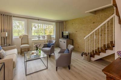 Panier de fruits frais sur une table en verre avec deux cocktails colorés, entouré de fauteuils en rotin.