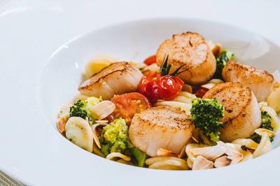 Panier de fruits frais sur une table en verre avec deux cocktails colorés, entouré de fauteuils en rotin.