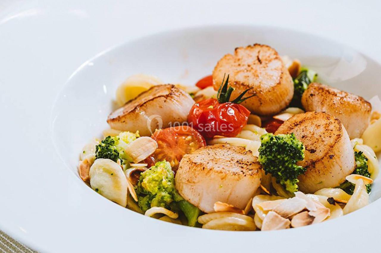 Assiette de pâtes garnie de noix de Saint-Jacques poêlées, brocolis, tomates cerises et amandes effilées.