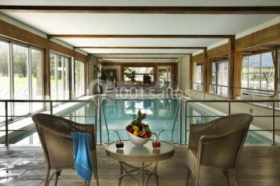 Panier de fruits frais sur une table en verre avec deux cocktails colorés, entouré de fauteuils en rotin.