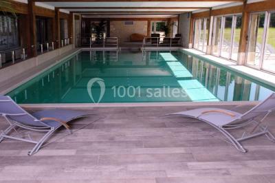 Panier de fruits frais sur une table en verre avec deux cocktails colorés, entouré de fauteuils en rotin.