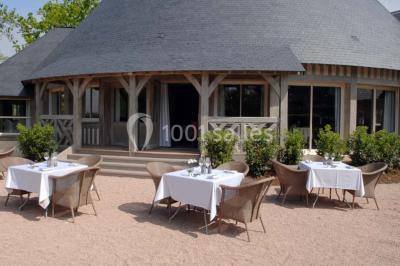 Panier de fruits frais sur une table en verre avec deux cocktails colorés, entouré de fauteuils en rotin.