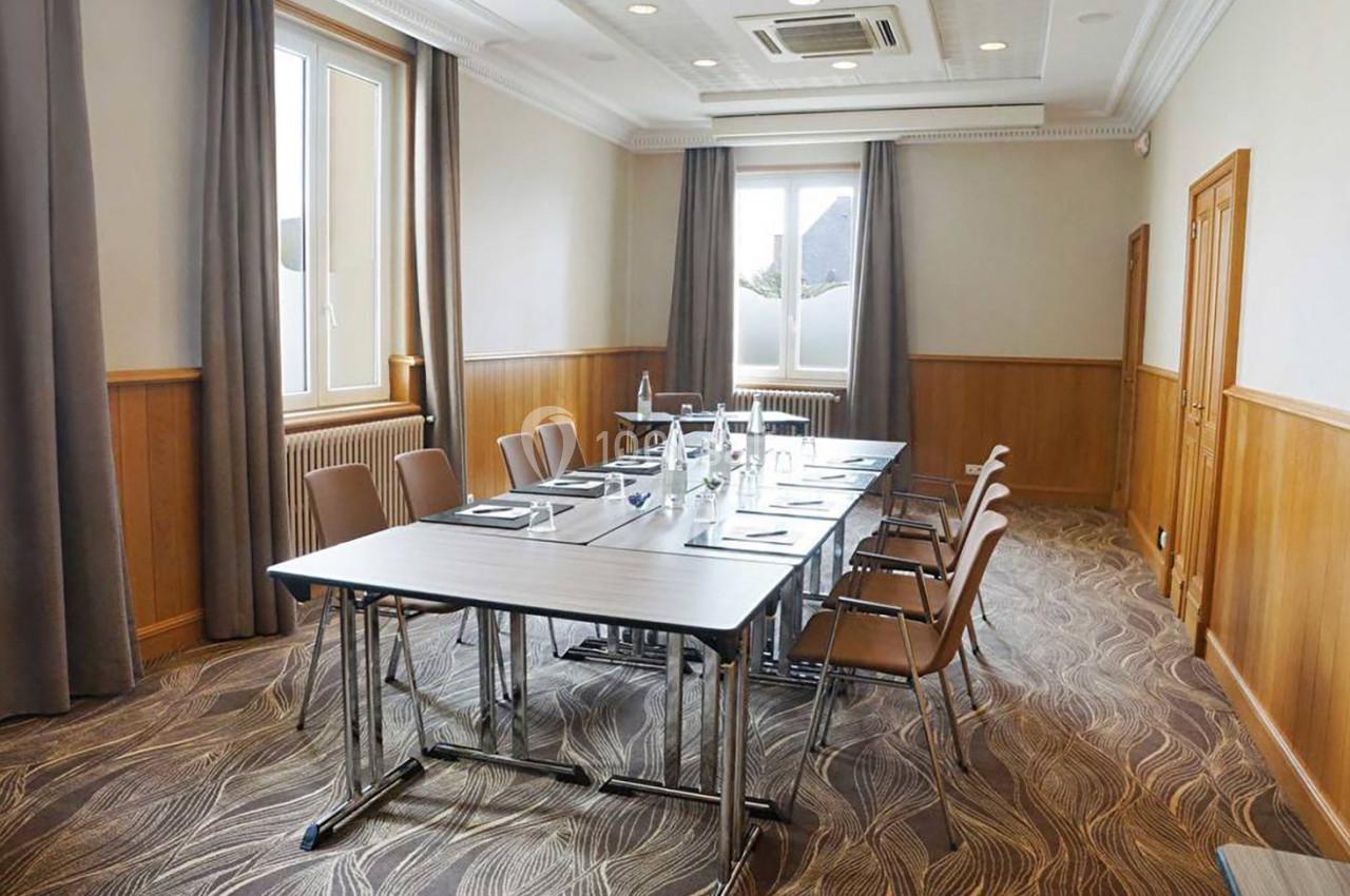 Salle de réunion lumineuse avec une table rectangulaire, des chaises, des bouteilles d'eau et des fenêtres donnant sur l…