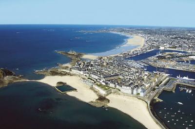 Vue aérienne de Saint-Malo, montrant les remparts, la plage, le port et les environs côtiers sous un ciel dégagé.