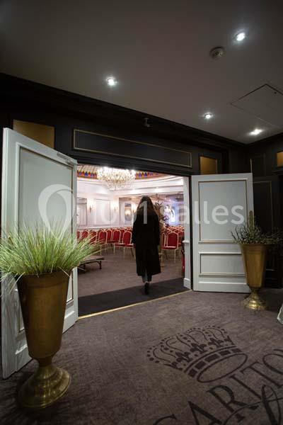 Une femme entre dans une salle de conférence élégante avec des chaises rouges et un lustre au plafond.
