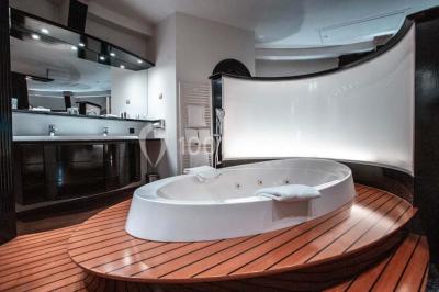 Un homme court sur un tapis de course dans un spa, une femme en peignoir est assise en arrière-plan.