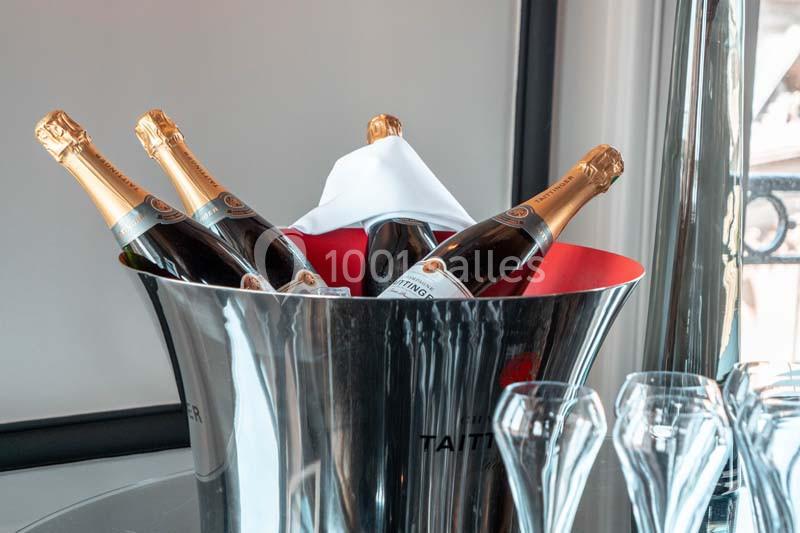 Seau en métal contenant quatre bouteilles de champagne avec des verres à pied en verre posés à côté.