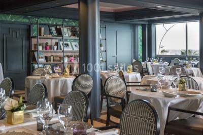 Chambre lumineuse avec un canapé rose, un lit double aux coussins jaunes et une table décorée de fleurs.
