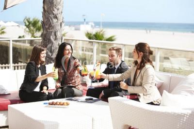 Chambre lumineuse avec un canapé rose, un lit double aux coussins jaunes et une table décorée de fleurs.
