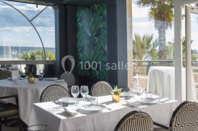 Chambre lumineuse avec un canapé rose, un lit double aux coussins jaunes et une table décorée de fleurs.