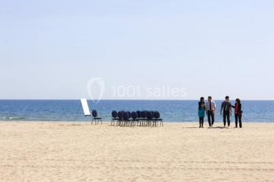 Chambre lumineuse avec un canapé rose, un lit double aux coussins jaunes et une table décorée de fleurs.