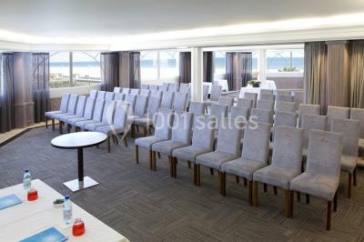 Chambre lumineuse avec un canapé rose, un lit double aux coussins jaunes et une table décorée de fleurs.