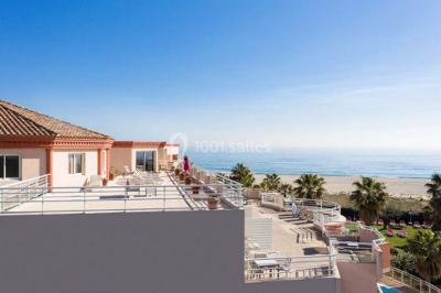 Chambre lumineuse avec un canapé rose, un lit double aux coussins jaunes et une table décorée de fleurs.