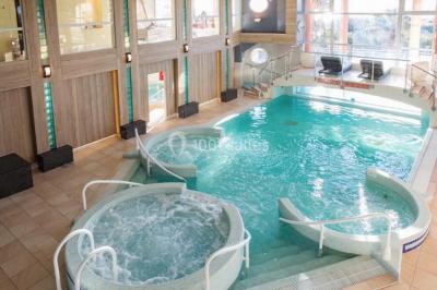 Chambre lumineuse avec un canapé rose, un lit double aux coussins jaunes et une table décorée de fleurs.