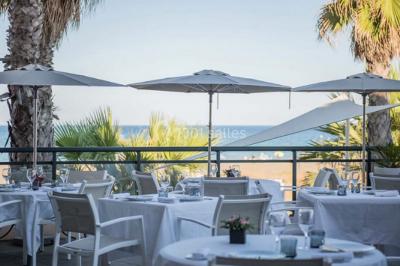 Chambre lumineuse avec un canapé rose, un lit double aux coussins jaunes et une table décorée de fleurs.