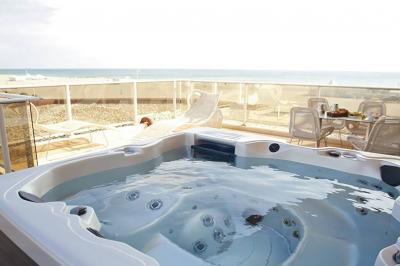 Chambre lumineuse avec un canapé rose, un lit double aux coussins jaunes et une table décorée de fleurs.