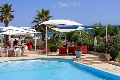 Chambre lumineuse avec un canapé rose, un lit double aux coussins jaunes et une table décorée de fleurs.