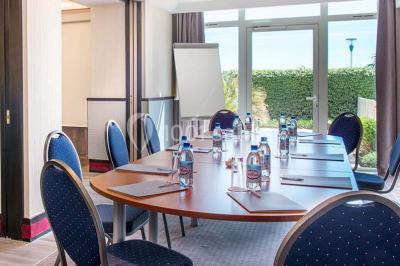 Chambre lumineuse avec un canapé rose, un lit double aux coussins jaunes et une table décorée de fleurs.