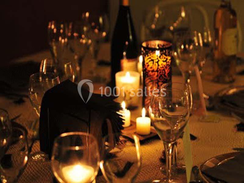 Table dressée avec des verres, des bougies allumées et une bouteille de vin dans une ambiance tamisée.