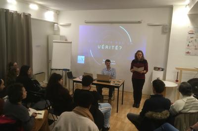Un groupe de personnes assiste à une présentation sur le thème de la vérité dans une salle de réunion.