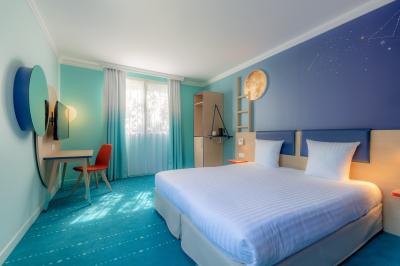 Salle de conférence lumineuse avec rangées de chaises alignées, écran de projection et portes vitrées au fond.