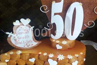 Chaises et tables en fer forgé disposées sous un grand arbre dans un jardin verdoyant, éclairé par la lumière du jour.