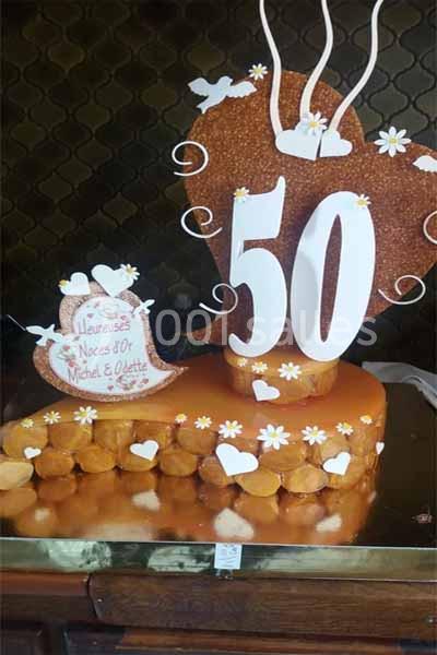 Gâteau décoratif pour des noces d'or avec le chiffre 50, des cœurs, des fleurs et des papillons blancs.