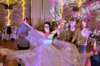 Une mariée danse au centre d'une salle décorée de guirlandes lumineuses, entourée d'invités.