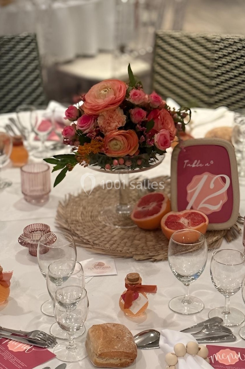 Table dressée avec une décoration florale colorée, des verres, un menu, du pain et des éléments décoratifs fruités.