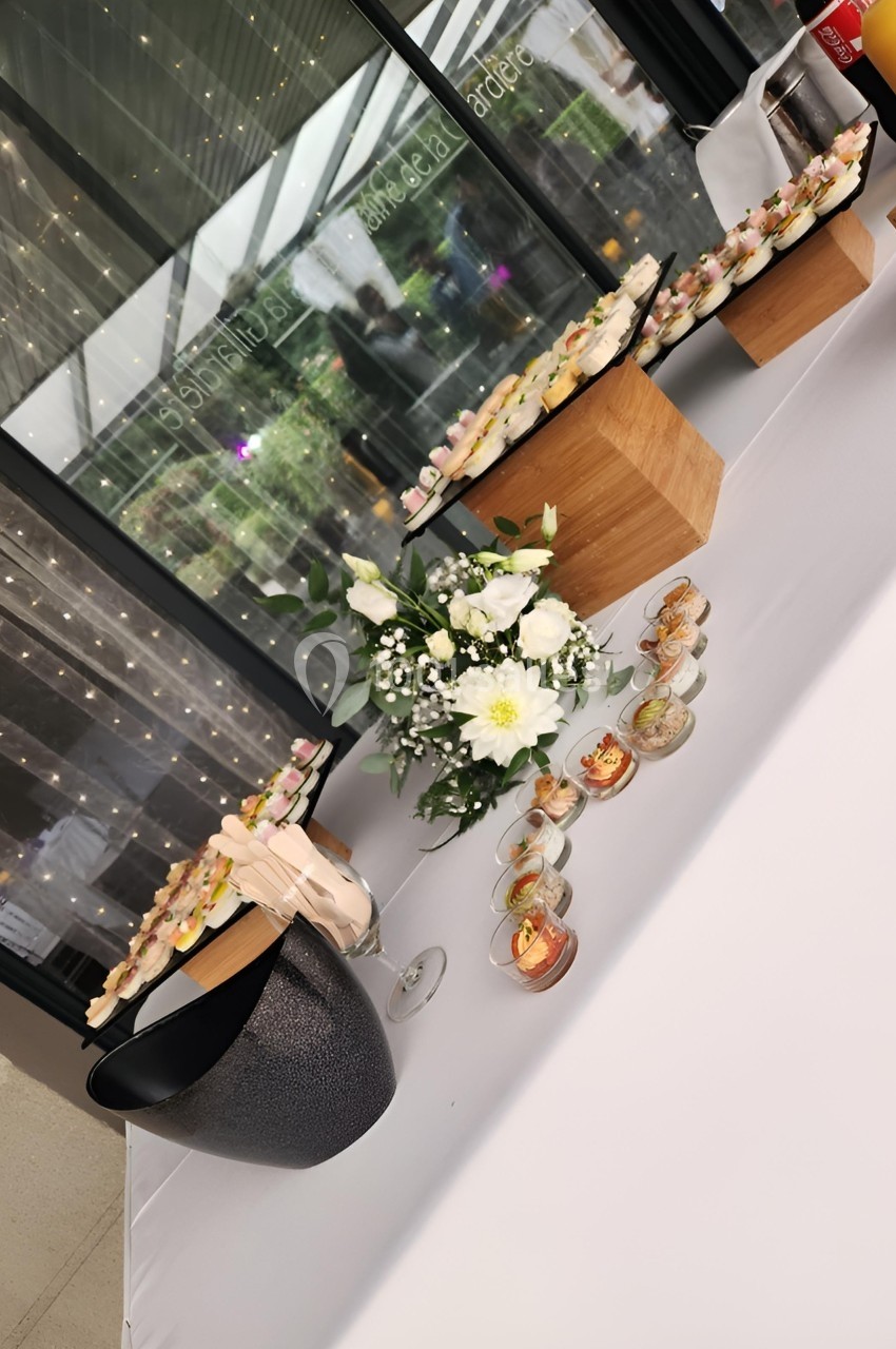 Table décorée avec des fleurs blanches, des verrines et des amuse-bouches disposés sur des présentoirs en bois.