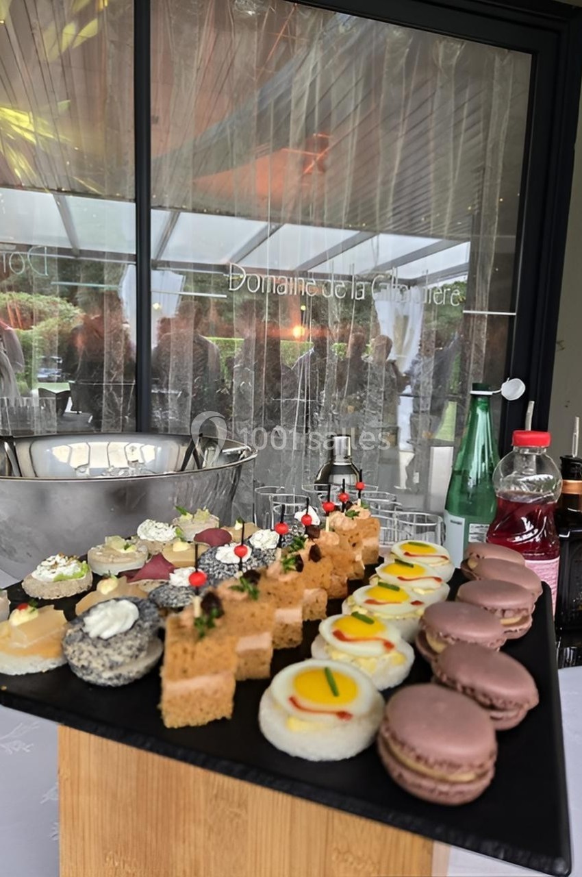 Plateau de desserts variés comprenant macarons, mini-gâteaux et bouchées sucrées, présenté sur une table lors d'un événement.