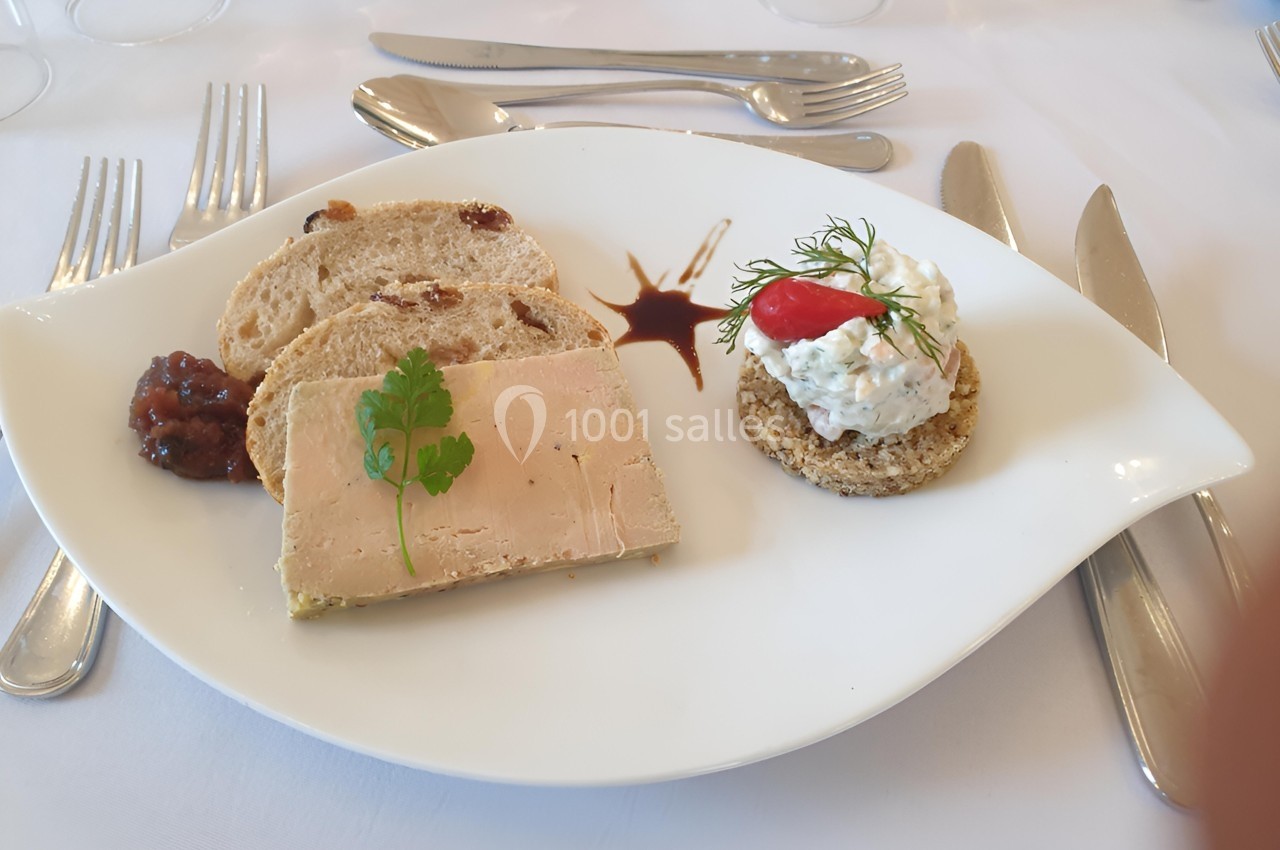 Assiette avec tranche de foie gras, pain aux fruits secs, chutney, et toast garni de crème et aneth.