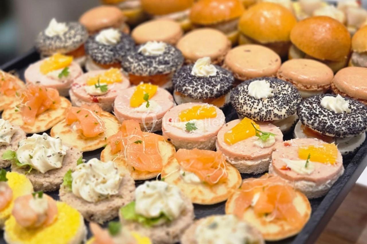 Plateau de canapés variés avec saumon, crevettes, mousse et garnitures colorées, disposés sur une table.